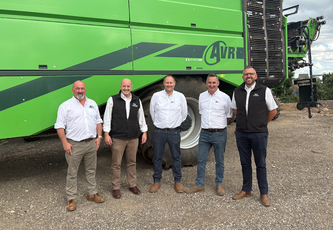 Five men standing in front of large green agricultural machine