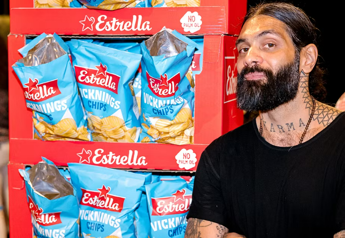 Artist in black T shirt posing with packets of crisps used in art display