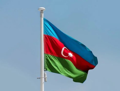 Blue, red and green flag on pole blowing in breeze against blue sky background