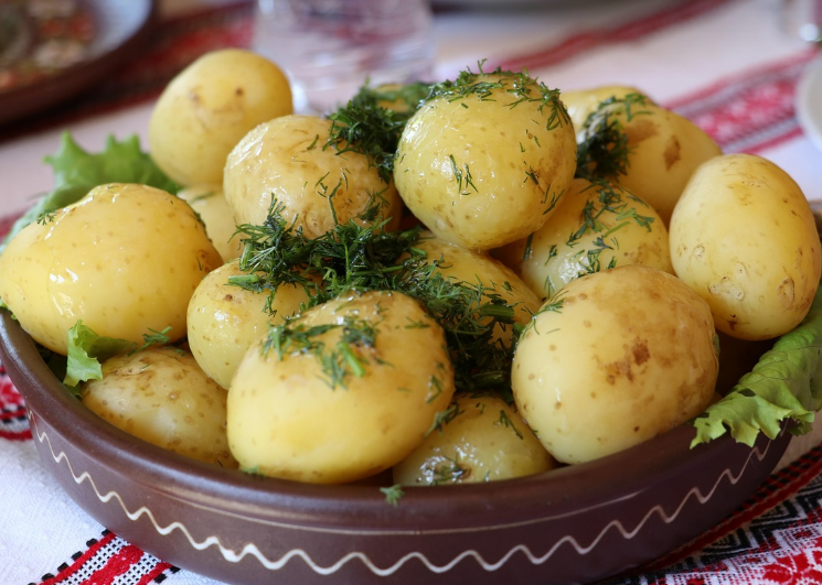 Cooked potatoes in ceramic Arabic-style bowl with herbs and butter on top