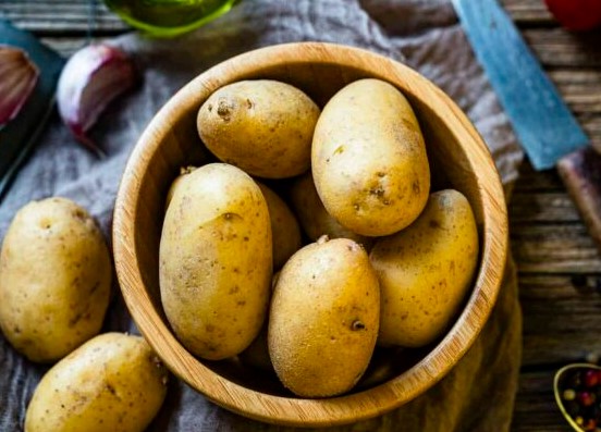 potatoes in wooden bowl on table cloth