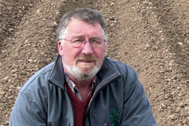 Man crouching down in ploughed potato field