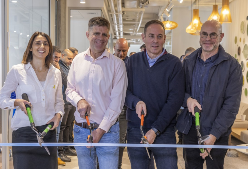 Three men and one woman with shears cutting ribbon to mark a centre opening