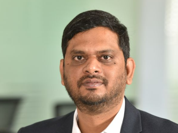 Indian man with beard and mustache wearing white shirt and grey jacket