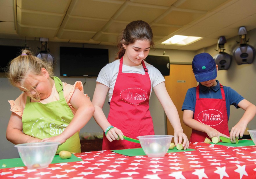 Children making recipes on red and white table cloth
