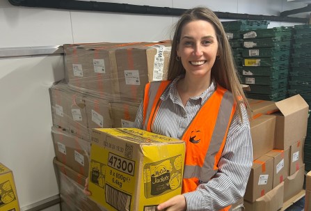 young woman wearing high-vis jacket holding box