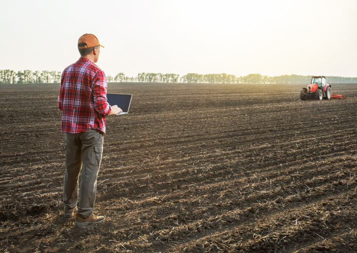 Farmer with electronic tablet in potato field assessing soil