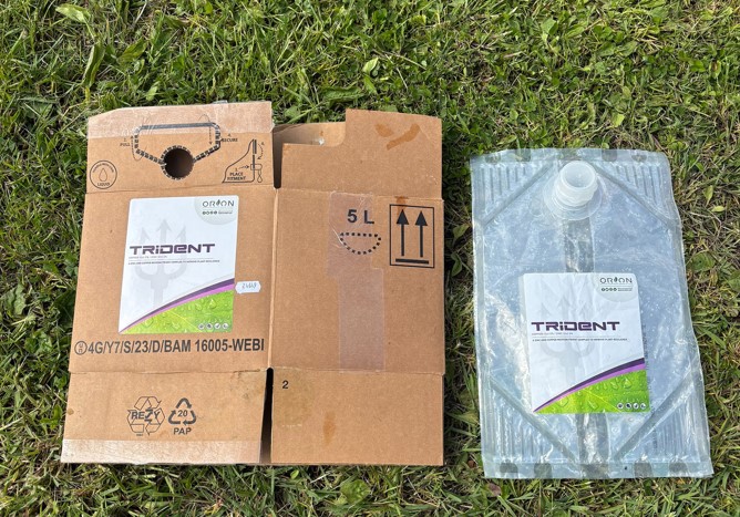 Cardboard flat box and plastic bag lined up on green background