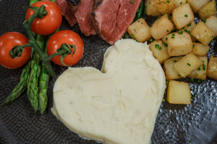 HEART SHAPED MASHED POTATO AND POTATO ROSTI ON PLATE WITH TOMATOES AND MEAT