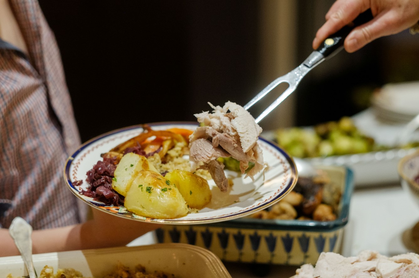plate with potatoes and turkey on, and hand withy fork
