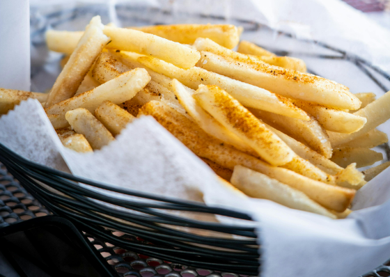 French fries or cheaps on a napkin in a wire dish with seasoning on top