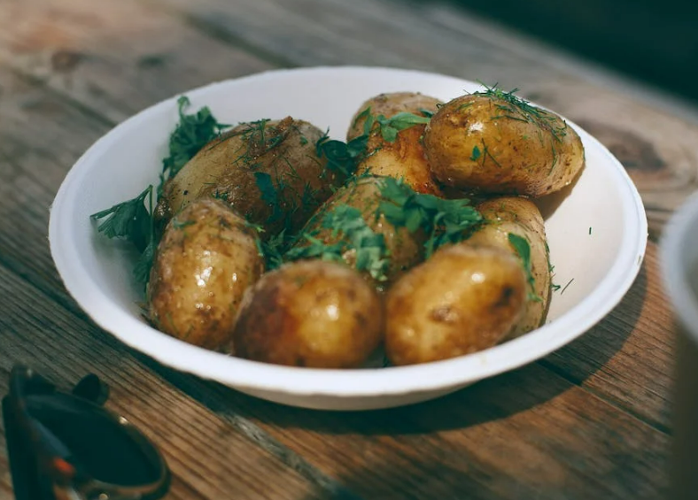 Potatoes with skins on and herbs in bowl