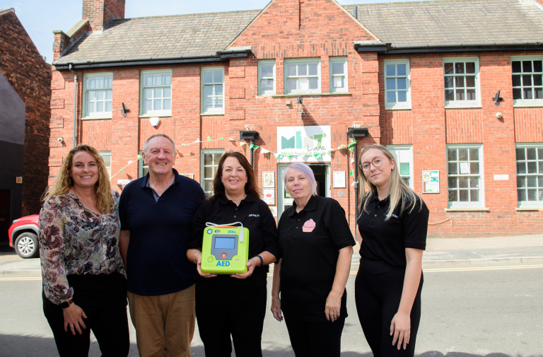 Ladies receiving donated defibrillator from man