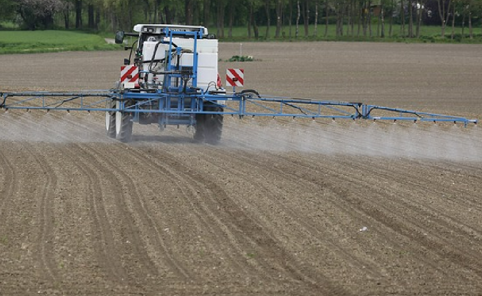 tractor with boom applying pesticide in field