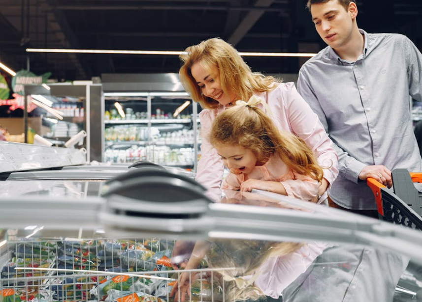 shoppers shown looking at frozen products while pushing trolley in store